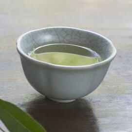 A photo of a small white teacup with green tea in it. This picture takes you to the kin section